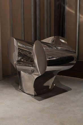 Chair composed of reflective, curved metal