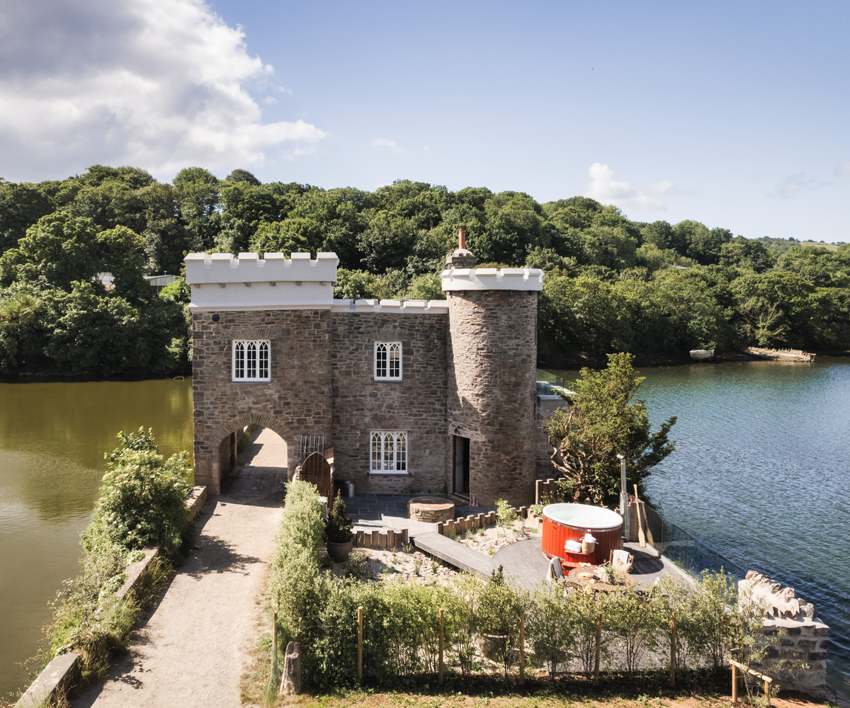 castle-style building with lake on either side and trees in background