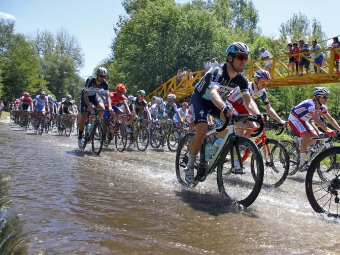 The riders pass through a stream that crosses the road