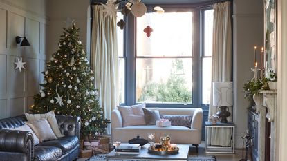 A well-decorated Chriistmas tree in a neutral living room