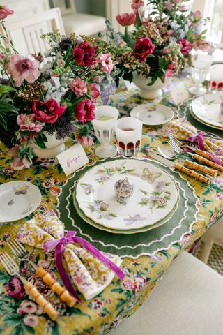 dinner table with flowers, floral table cloth, plates, and utensils