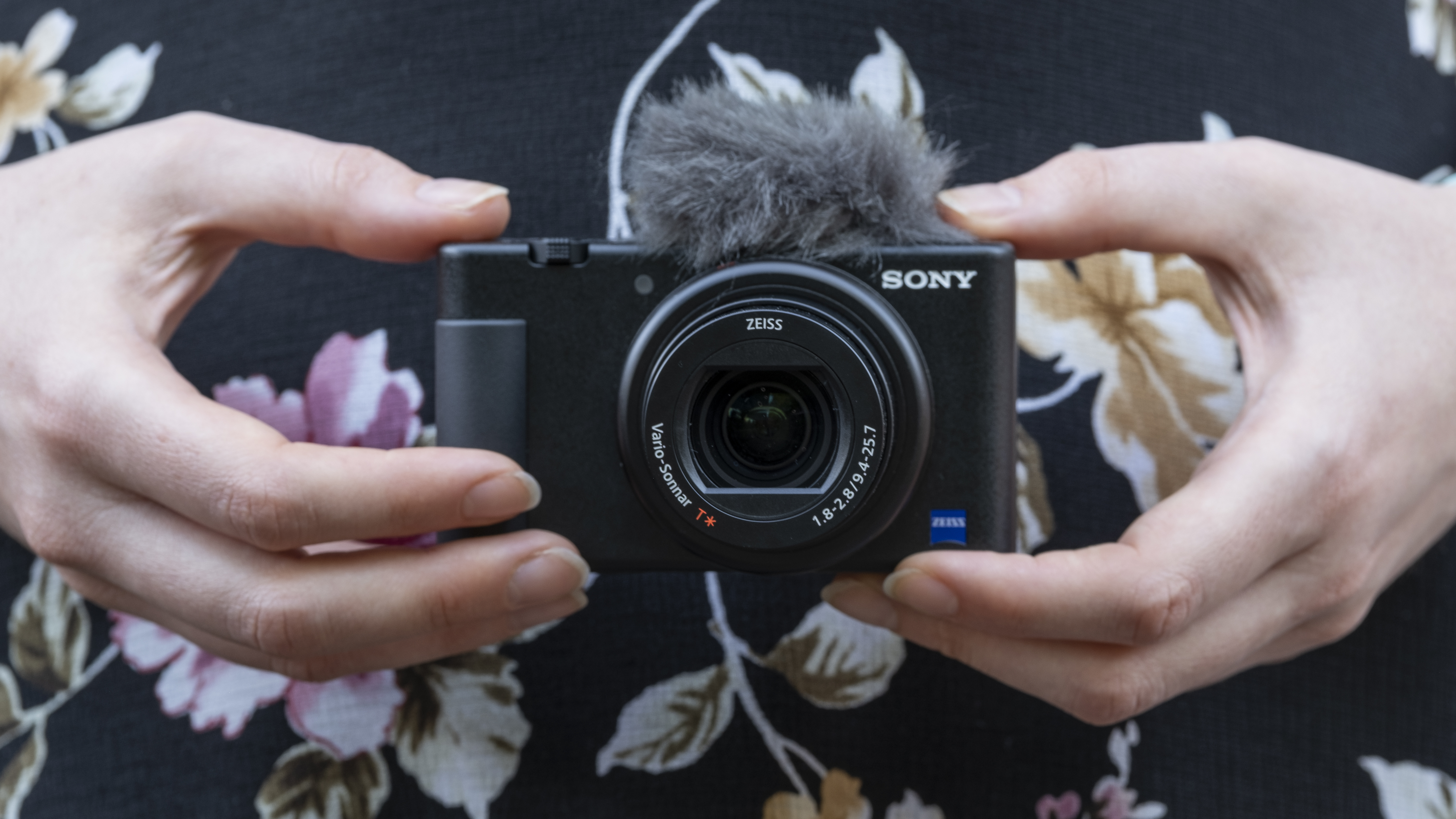 Two hands holding the Sony ZV-1 with its microphone windshield