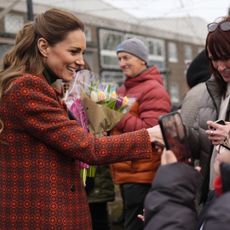Princess Kate wearing an orange coat and shaking hands with fans