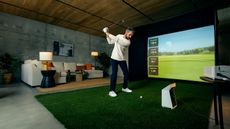 A golfer hits a shot in a simulator