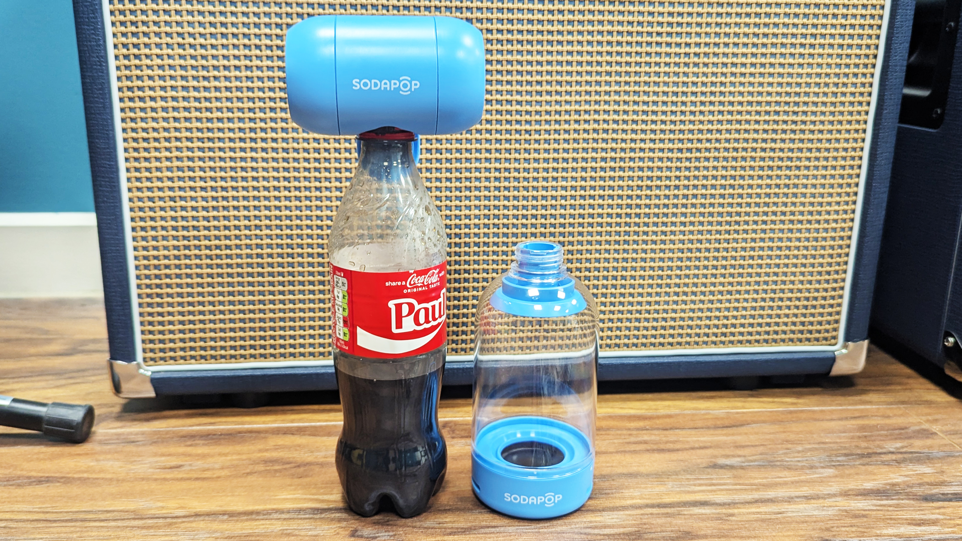 A Sodapop Bluetooth speaker sitting atop a Coca Cola bottle