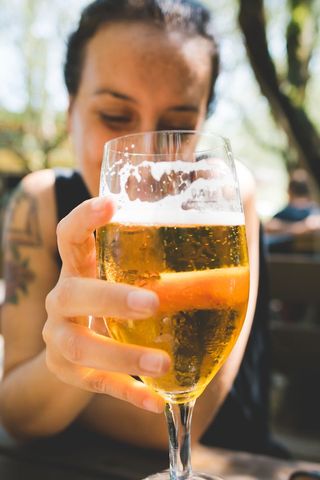 A woman holding up a glass of beer