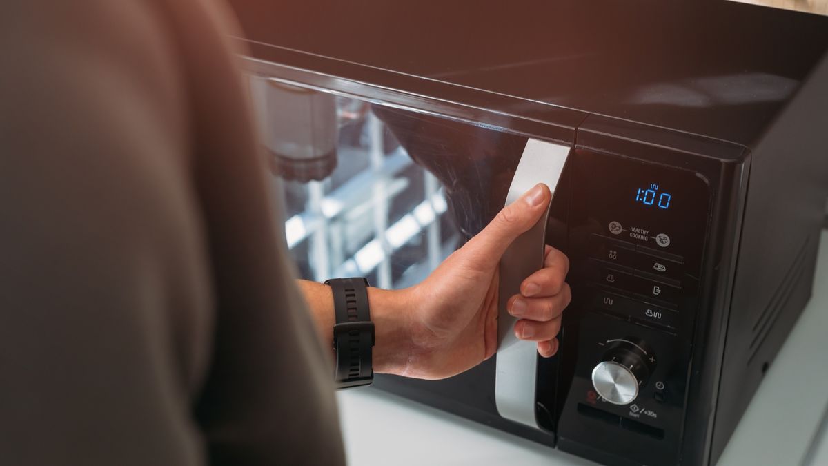 Close up of man using microwave in kitchen