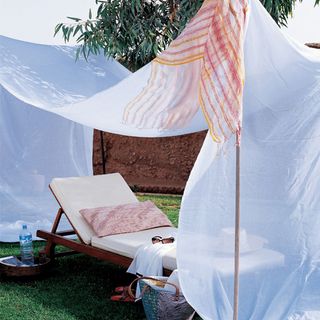 White canopy over white sun lounger with pink cushion