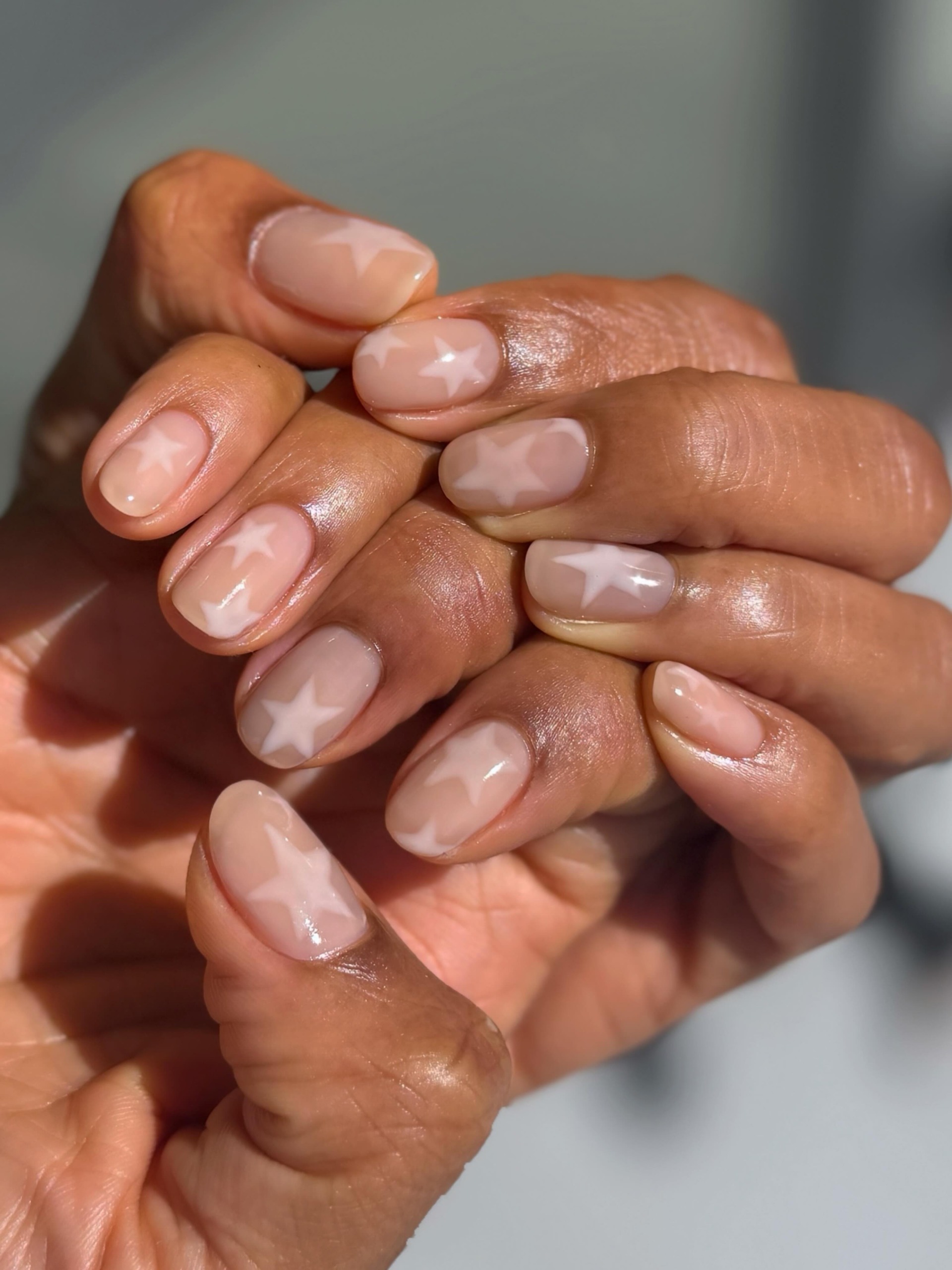 little white stars scattered over sheer pink nails short rounded shape
