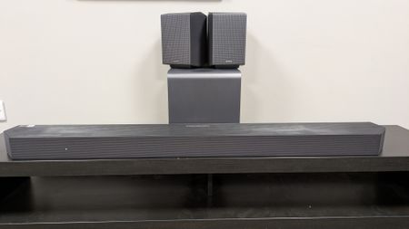 Samsung HW-Q990H soundbar system with the soundbar in front, subwoofer behind and rear speakers stacked on subwoofer 