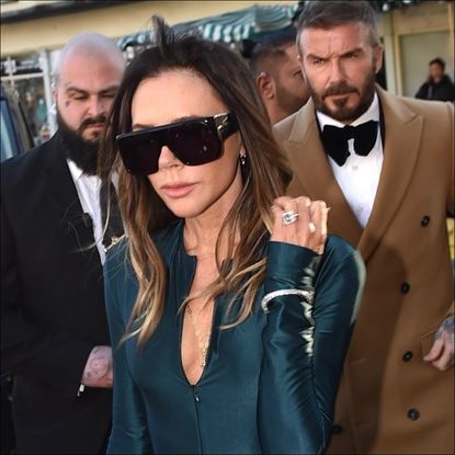 Victoria Beckham wears a gown from her own label paired with a fur shawl and a silver box clutch