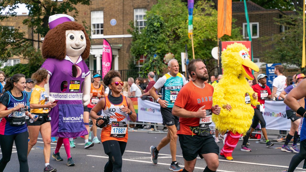 LONDON, UNITED KINGDOM - 2022/10/02: Some runners seen in fancy costumes as they run past mile 21 during the London marathon. For the first time a stretch of the London Marathon route was transformed into Rainbow Row to celebrate the LGBTQIA+ community, promote inclusivity and create a party atmosphere. Marathon runners passed two stages with music and drag performances. Butchers Row in Limehouse was covered with colourful flags and buntings. 