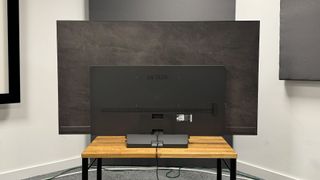 65-inch LG C4 TV on a wooden stand, photographed from behind.