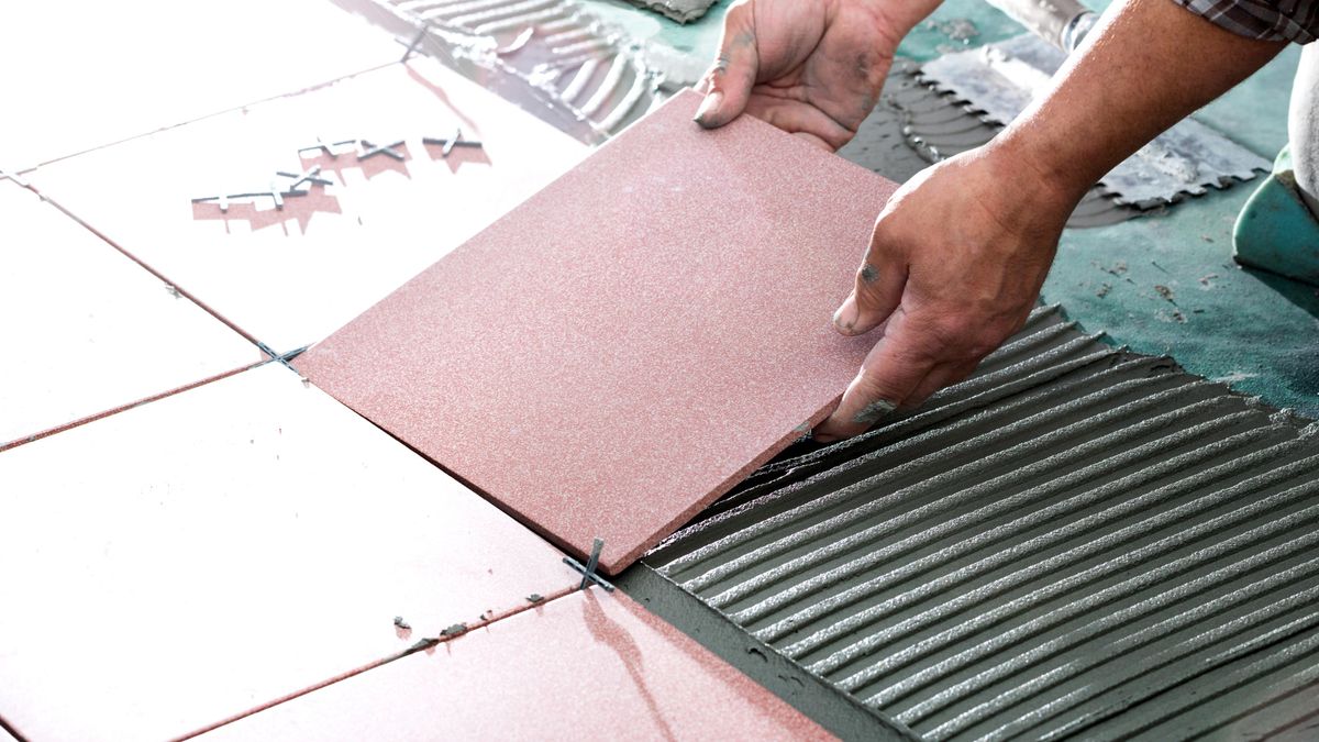 Person laying tiles on floor