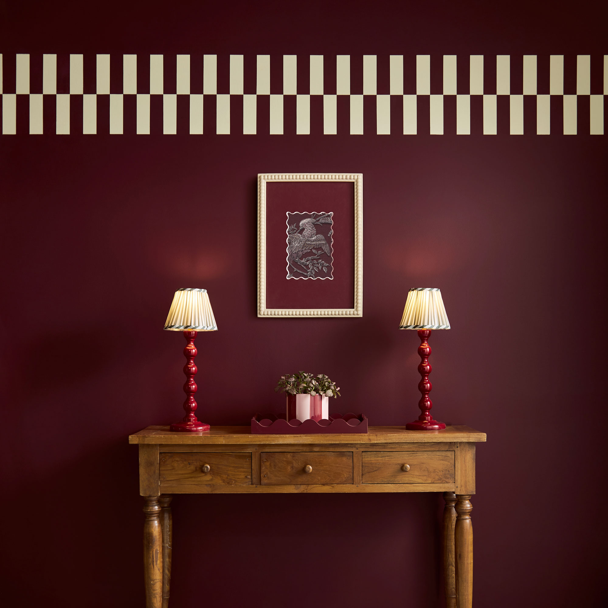 Divine Damson red on the walls of a hallway with a wooden console table and two table lamps