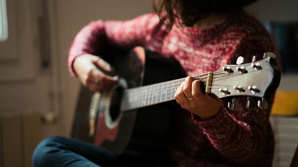 Woman playing guitar at home