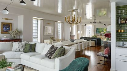 open plan living room with white walls white sectional sofa and view to dining room with white table and chairs