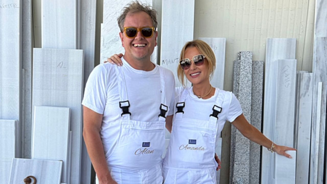 Amanda and Alan at a stone merchants in Greece, wearing white dungarees, white t-shirts and sunglasses