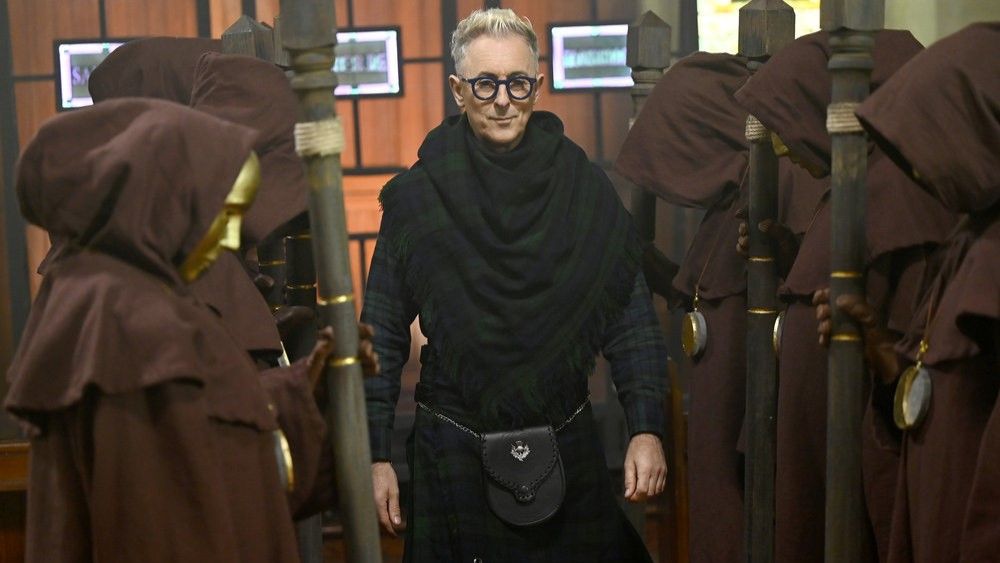 Alan Cumming surrounded by people in robes in The Traitors US season 2