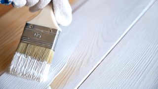 Close up of paintbrush painting wood with whitewash
