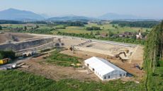 Excavation tent in the foreground at Cham-&Auml;bnetwald, with green countryside and mountains in the distance.