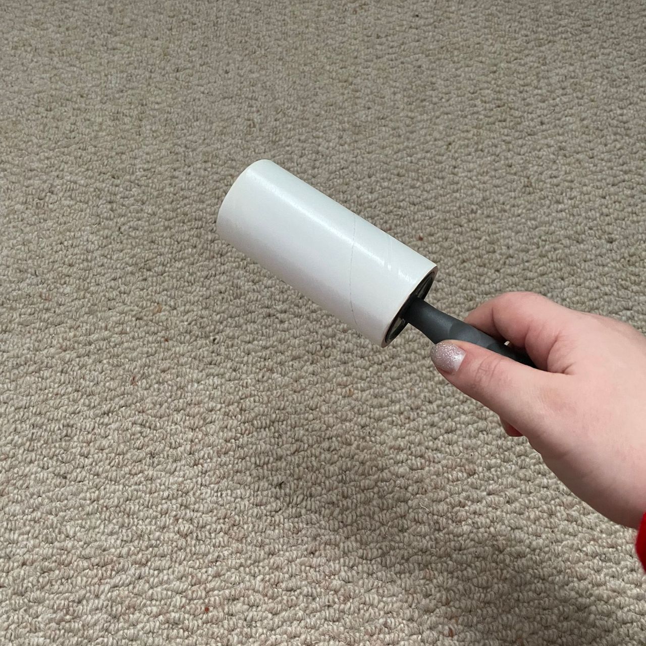 Holding a clean lint roller above cream carpet