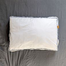 The Emma Original Hybrid Pillow being tested on a bed with a grey linen duvet cover