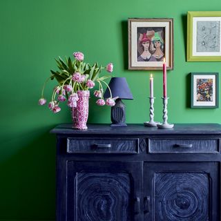 Green wall with navy storage unit with flowers and candles
