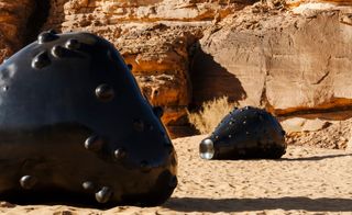 Metetorite-like giant black sculptures place in desert