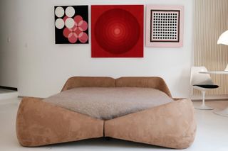 artworks on wall above curved retro bed