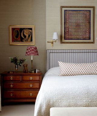 Bedroom with textured cream walls, striped headboard and wooden drawers as a bedside table