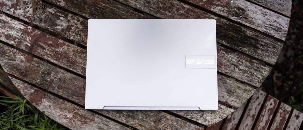 A silver ASUS Vivobook Pro 16X OLED laptop sitting on a wooden table