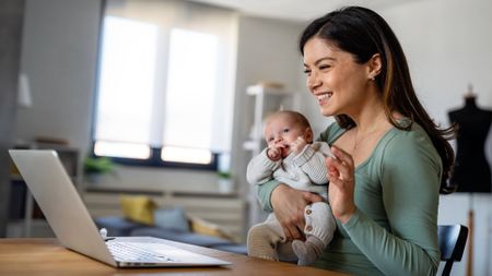 Happy young mother with baby having video call