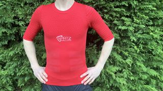 Man wearing red short-sleeved base layer by hedge