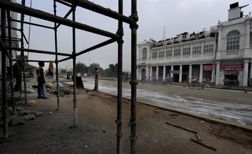 Cyclists ride past under-renovation shops in Connaught Place in New Delhi.