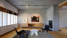 modern living room with bamboo floor, concrete walls, built-in shelving, floating timber vanity, artwork, two chairs and a white coffee table