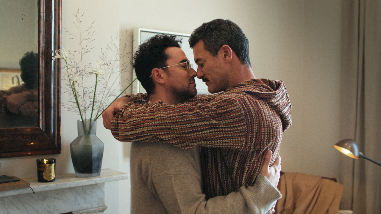 Daniel Levy and Luke Evans embracing in their apartment in Good Grief.