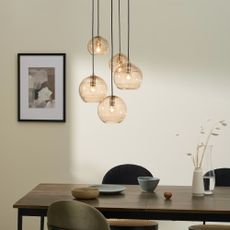 A glass pendant light over a wooden dining table