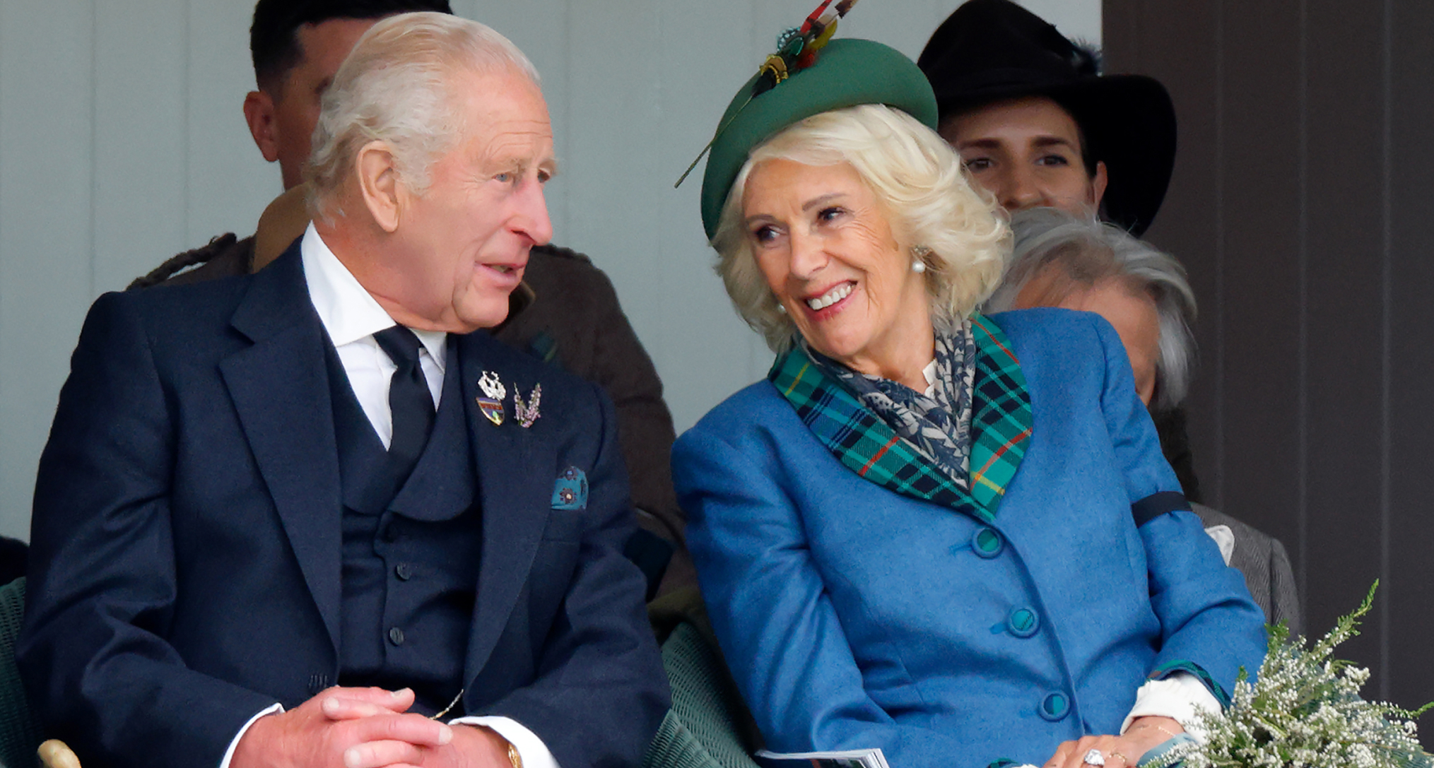 King Charles and Queen Camilla smiling at each other sitting in chairs