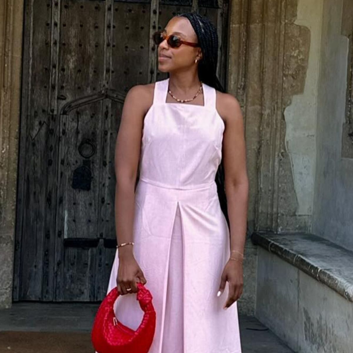 Woman wears pink dress from Aligne and red handbag
