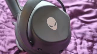 The left earcup of the Alienware Pro Wireless Gaming Headset showing the Alienware logo on a purple background.