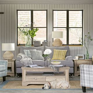 Country style living room with wall panelling black window frames and grey sofa