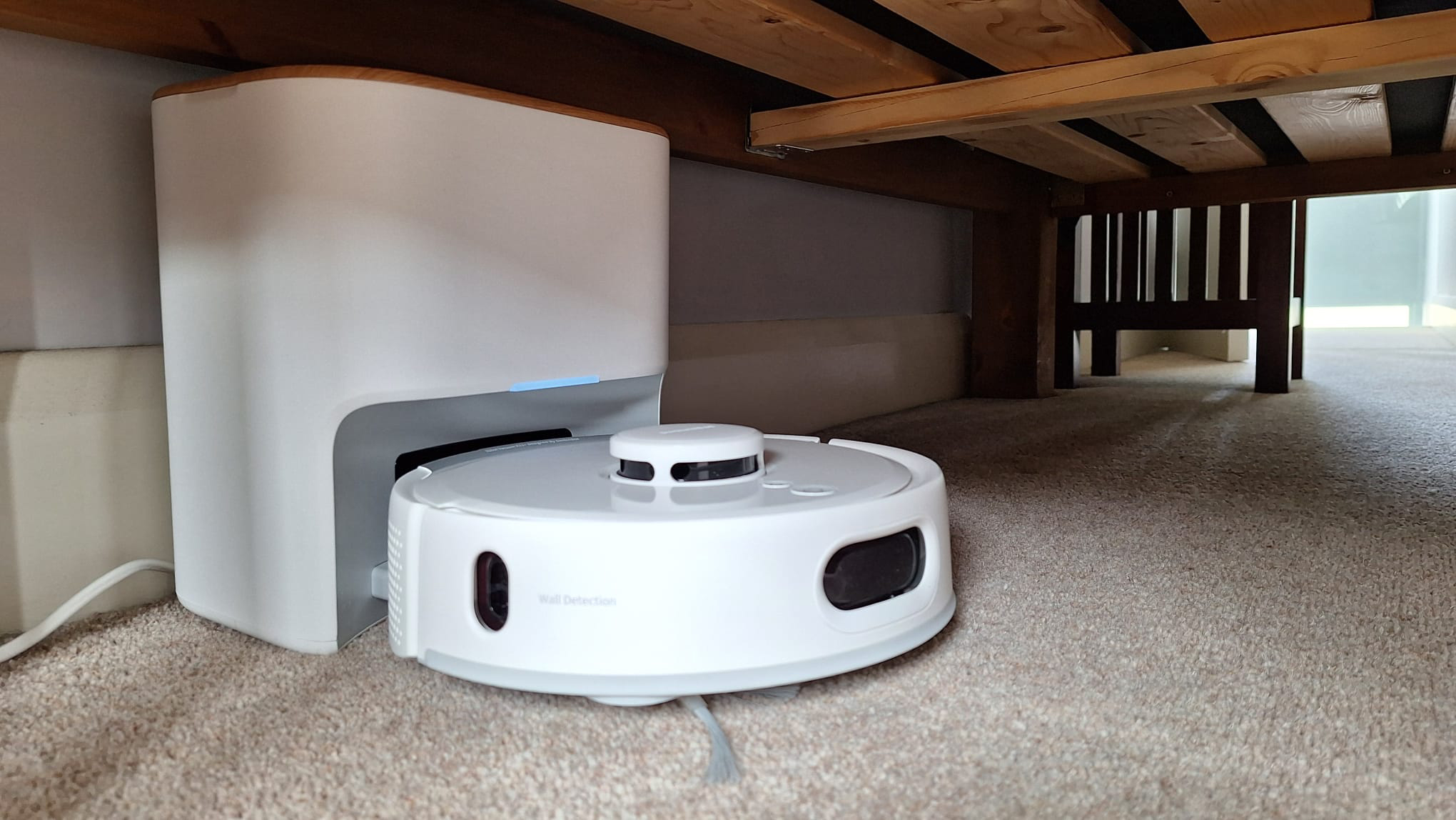 SwitchBot K11+ in its dock, under a bed