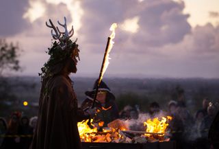 A man representing the Winter King holds a flaming sword as he takes part in a ceremony as they celebrate Samhain at the Glastonbury Dragons Samhain Wild Hunt 2017