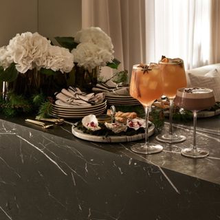 H&M marble serving board with metal handle on black marble surface with bouquet of white flowers