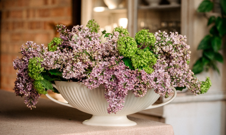 floral design of lilac and green viburnum opulus in white ceramic boat vase