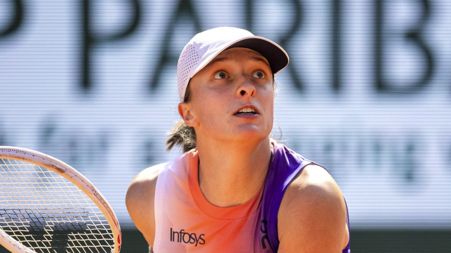 Iga Swiatek of Poland, holding a tennis racquet, tenses her body in preparation to return a tennis ball during her match against Coco Gauff of the United States on Court Philippe-Chatrier ahead of the 2024 French Open Tennis Final at Roland Garros.