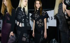 Four women in black outfits with geometric designs and panels