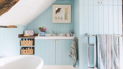 coastal bathroom with metal vanity unit and sink, bare wood on walls, vintage mirror, wall lights, stone floor, shower to right