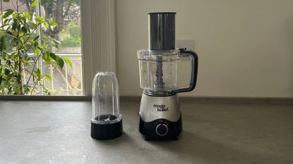 Magic Bullet Kitchen Express on the countertop with the food processor attachment on top and the blender beside it